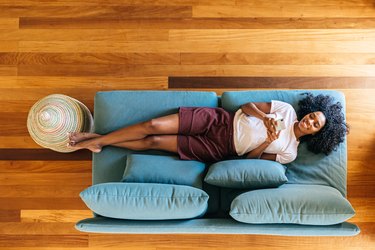 Black woman resting on her couch at home, as a natural remedy for menstrual cramps