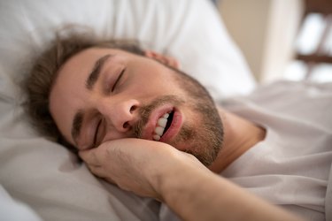 Young man in bed and drooling in his sleep