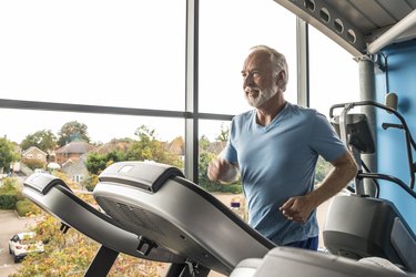 Older adult using treadmill in gym wearing blue T-shirt
