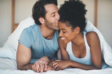 A couple cuddling in bed together before sleeping in separate beds