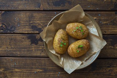 Oven-baked potatoes with spices and olive oil on dark wooden table