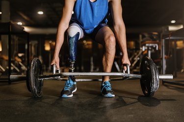 strong man with prosthetic leg doing a hex bar deadlift in the gym