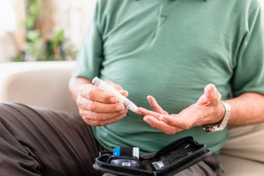 Senior man checking blood sugar level at home