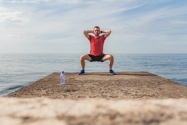 Person doing a sumo squat, the starting position of a platypus walk, on beach