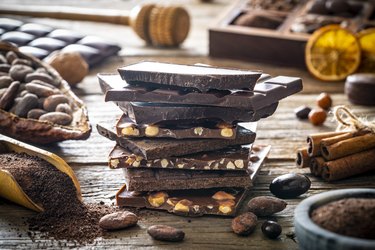 Chocolate bars with nuts stacked and cocoa beans powder spoon