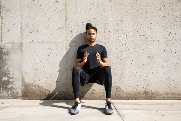 fit Black man doing a wall sit outdoors as part of a 5-minute leg workout