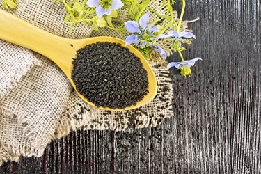 Seeds of black cumin in spoon on board top