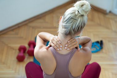 Woman rubbing her neck because of a muscle cramp, a symptom of low magnesium