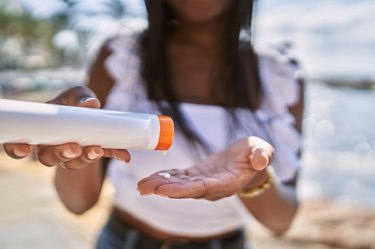 close view of a person on the beach putting sunscreen lotion in their hands