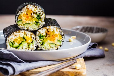 Healthy veggie sushi rolls with rice, hummus, vegetables and seedlings.