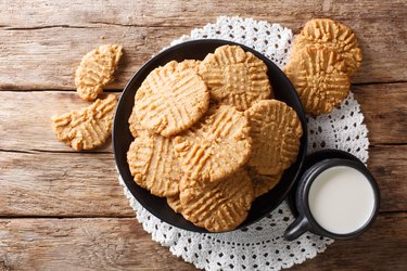 Plate of butter cookies baked with a butter substitute on wooden table with glass of milk on side