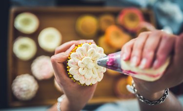 Hands decorating cupcakes with icing made with corn syrup substitute