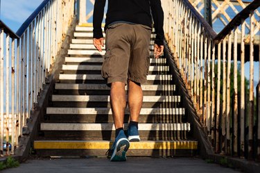 Rearview of a person wearing sneakers and shorts and climbing a flight of outdoor stairs