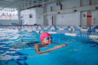 Swimmer in pool wearing swim cap and goggles