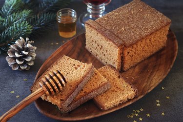 Christmas spice gingerbread cake and honey on a dark table with pinecone on the side