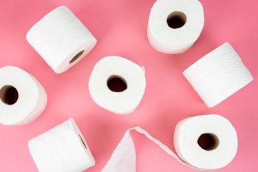 Top view of rolls of toilet paper on a pink background