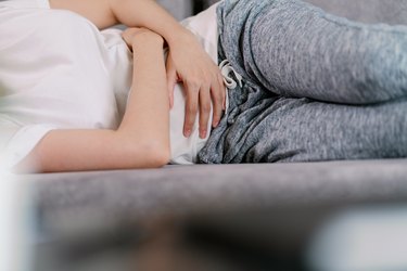 woman holding her stomach with pain below the belt line on the left side