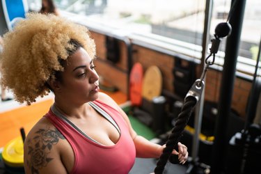 Young woman pulling weight machine at the gym, as an example of a non-scale victory