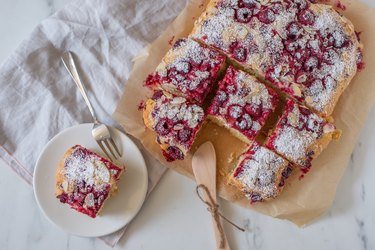 Raspberry cake cut into squares on parchment for raspberry breakfast recipes