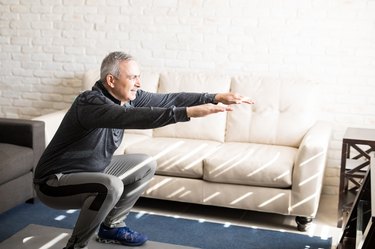 Mature man doing squats workout at home