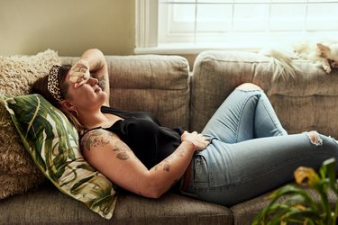 woman lying on the couch with stomach pain caused by a food intolerance