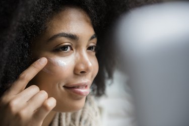 A woman applying zinc oxide ointment to her face to treat dark spots