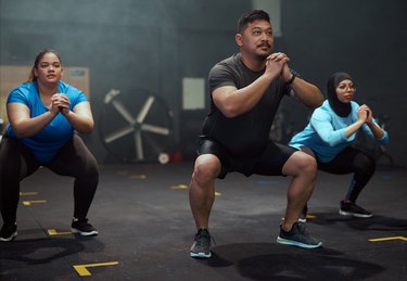 Full length shot of a diverse group of people holding a squat position during their workout in the gym
