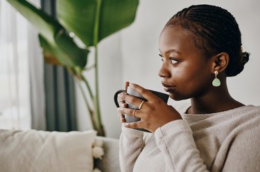 Shot of a young woman having coffee and relaxing at home