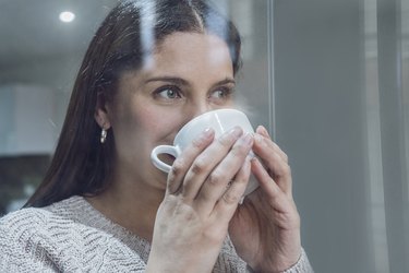 person drinking coffee at window