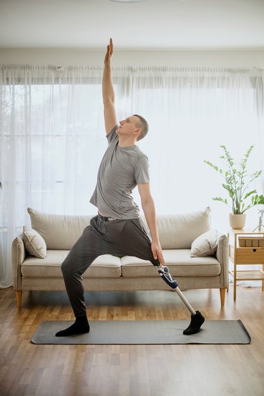 Person with prosthetic leg practicing yoga at home