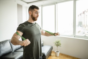 Sporty man  doing exercises with resistance band at home