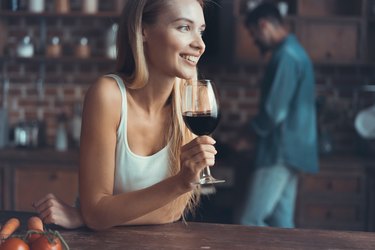 woman drinking some wine at home in kitchen .