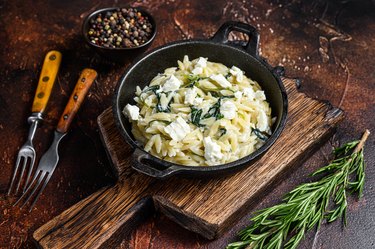 gluten-free Orzo primavera with green veggies spinach. Dark wooden background