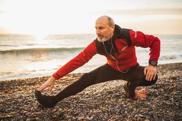 Older runner stretching their legs and warming up outdoors before running training