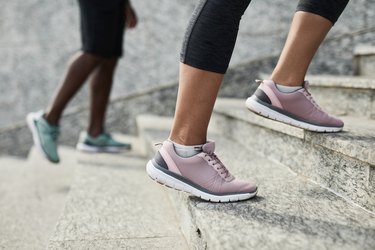 Two people wearing running shoes walking up granite stairs