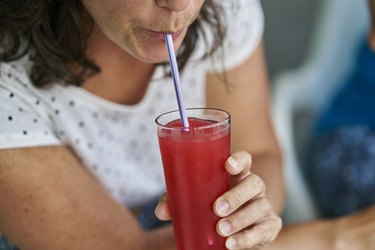 Close up of person drinking red juice, which you shouldn't do before a colonoscopy.