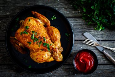 Roasted marinated chicken in a roasting dish on wooden table