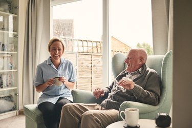 Senior man with COPD and female carer enjoying coffee at home