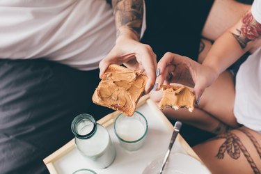 couple eating peanut butter toast in bed, as an example of foods that make you keep getting cavities