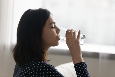 Young multiracial asian korean woman drinking cool distilled water.