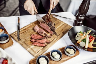 Hands of chef slicing grass-fed steak