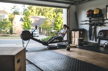 woman exercising on a rowing machine for cardio workout in home gym in garage