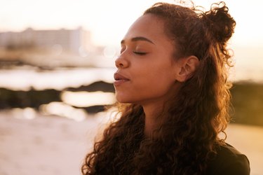 Close-up of a person meditating on the beach at sunset.