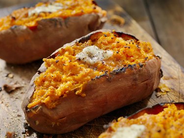 Biotin-rich sweet potatoes with a dollop of melted butter on a wooden board.