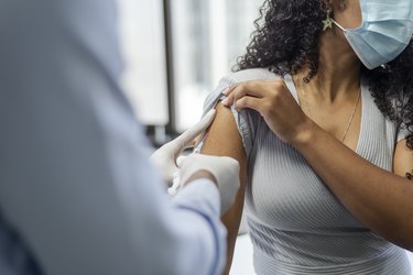 Close view of a person in a mask getting a flu shot