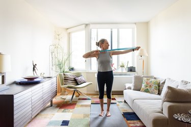 woman over 60 doing a resistance band workout in her living room
