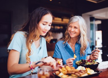 Older mother with daughter eating lunch together at restaurant