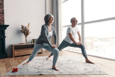 older couple doing balance exercises in their living room
