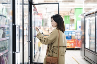 A woman is check a yogurt label for fat and calories in the supermarket