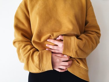 woman holding her stomach because she has lower intestinal bloating after drinking alcohol